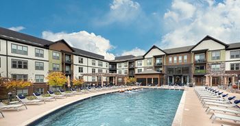 A  swimming pool with chaise lounge chairs in front of a building